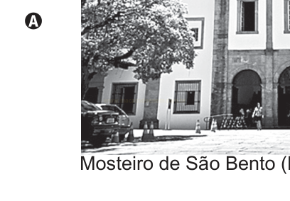 Fotografia em preto e branco de edifício colonial com árvore, carro estacionado e pessoas junto às arcadas.