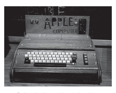 Fotografia em preto e branco de um computador antigo de madeira com teclado e a inscrição Apple Computer.