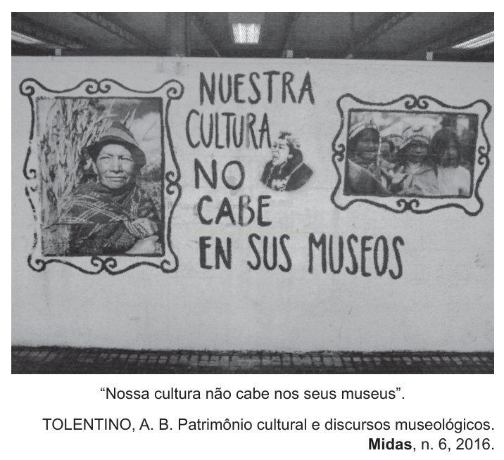 Fotografia em preto e branco de um mural com a frase "NUESTRA CULTURA NO CABE EN SUS MUSEOS" e dois retratos emoldurados.