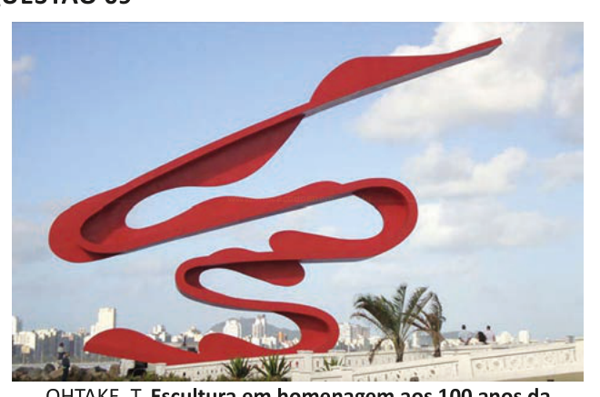 Fotografia de uma escultura vermelha em forma de traço sinuoso, semelhante ao número 100, diante de uma cidade.