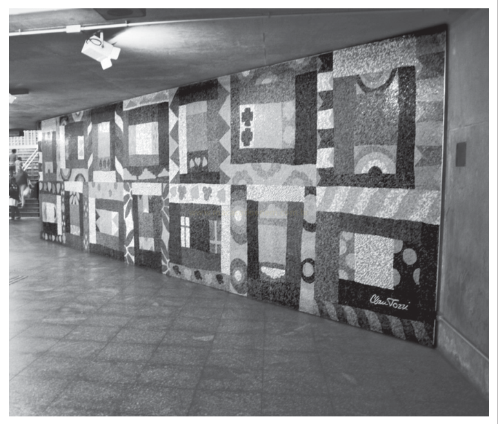 Fotografia em preto e branco de grande painel geométrico em parede de corredor subterrâneo, assinado Claudio Tozzi.